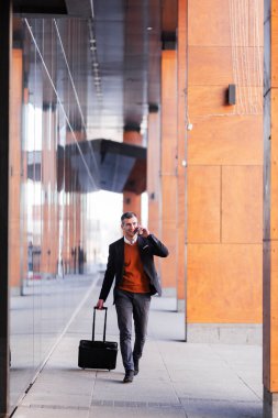 İş adamı yürüyor ve kahve içiyor. Tramvay bagajlı bir adam.