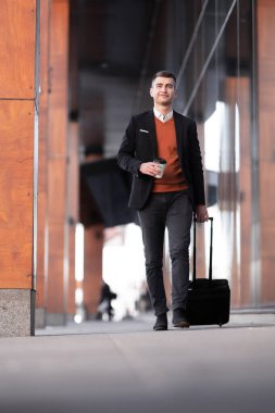 İş adamı yürüyor ve kahve içiyor. Tramvay bagajlı bir adam.