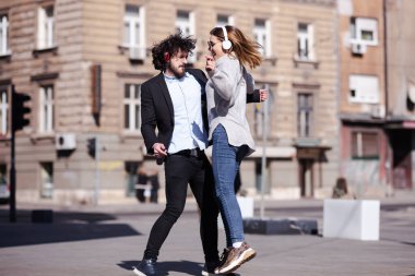 Genç iş arkadaşları işten sonra kulaklıkla dans ediyorlar. Mutlu arkadaşlar hoplayıp zıplıyorlar.