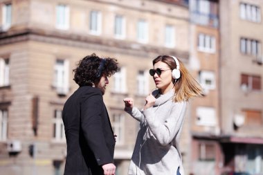 Genç iş arkadaşları işten sonra kulaklıkla dans ediyorlar. Mutlu arkadaşlar hoplayıp zıplıyorlar.