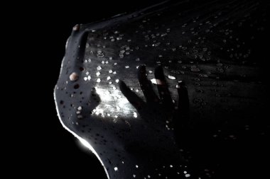 Soyut silüet eller geriliyor ve yarı şeffaf kumaşı arka planda küçük delikler ve ışık ile itiyor