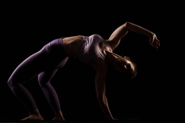 Stüdyoda yoga yapan formda bir kız. Yarı siluet yan aydınlatma fitness modeli