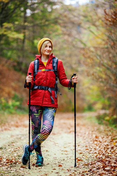带着柱子和背包的远足女孩站在小径上 看着摄像机 秋天外出旅游及健康生活 — 图库照片