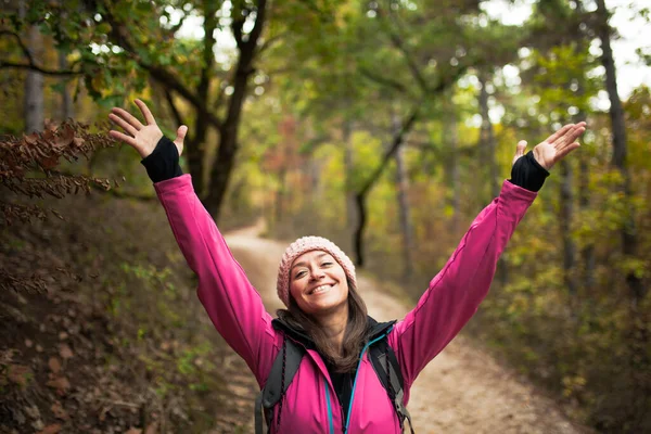 穿着粉色的远足女孩在森林里的小径上 在秋天的季节 举手表决大自然的落叶 — 图库照片