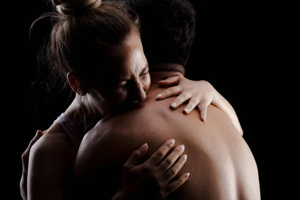 Fit couple posing together. Boy and girl side lit silhouettes on black background.