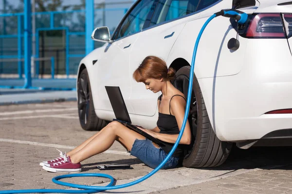 Dziewczyna Czeka Ziemi Kiedy Jej Elektryczny Samochód Się Ładuje Praca — Zdjęcie stockowe