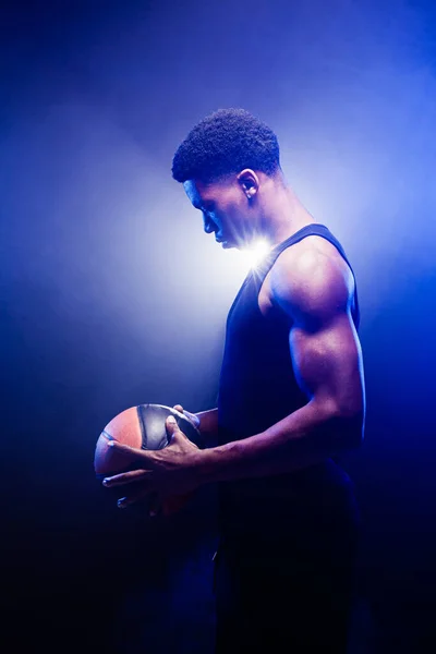 Koszykarz Trzyma Piłkę Tle Niebieskiej Mgły Afrykański Amerykanin Patrzy Koszyk — Zdjęcie stockowe