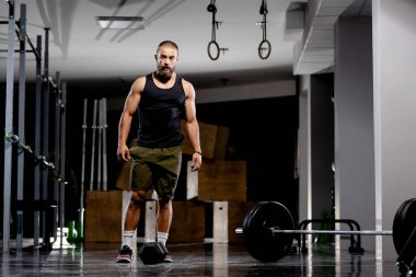 Kaslı sporcu ağırlık kaldırıyor. Ağır halterin yanında duruyor.. 