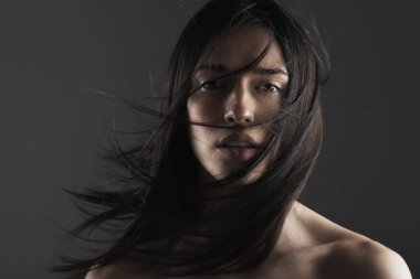 Yüzünün önünde rüzgarlı saçları olan güzel bir kızın moda stüdyosu portresi..