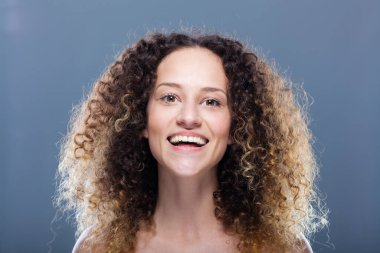 Uzun kıvırcık saçlı güzel esmer kız. Stüdyo portresi. Mutlu gülen yüz ifadesi.