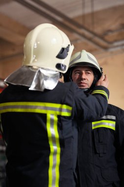 Üniforma giyen profesyonel itfaiyeciler. İtfaiyeci koruyucu kask takıyor..