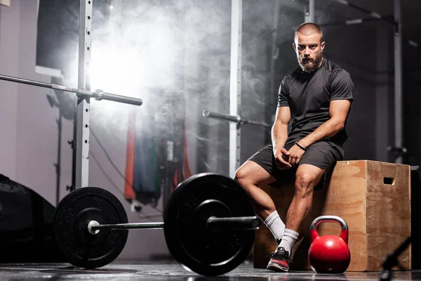 Muskelidrottare Poserar Med Tyngdlyftningsutrustning Rökbakgrund — Stockfoto
