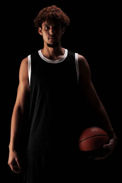 职业篮球运动员在黑色背景下持球 身穿运动服 高度集中的非洲裔美国人 — 图库照片