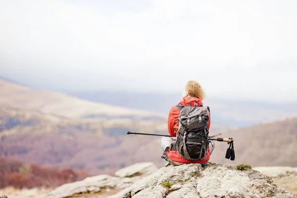 ハイカーの女の子は山の中の岩の上で休息を取る 冬の日だ 秋のアウトドア旅行と健康的なライフスタイル — ストック写真
