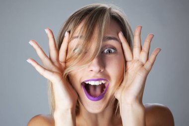 Güzel sarışın kız stüdyo resmi. El hareketleriyle şaşırmış yüz ifadesi..