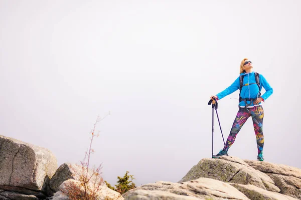 ポールとバックパックの岩の上に立ってハイキングの女の子 秋の風の日 秋のアウトドア旅行と健康的なライフスタイル — ストック写真