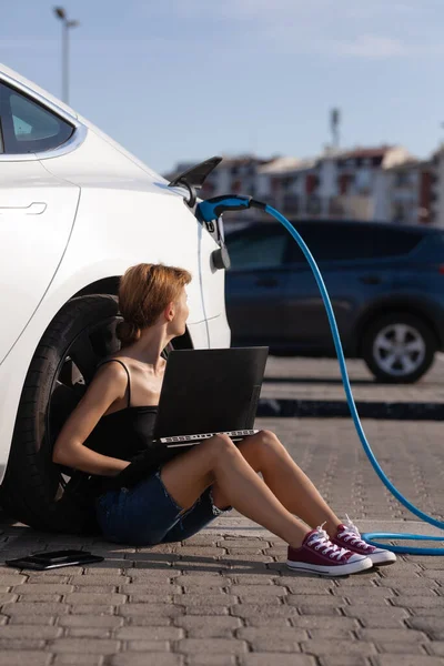 Dziewczyna Czeka Ziemi Kiedy Jej Elektryczny Samochód Się Ładuje Praca — Zdjęcie stockowe