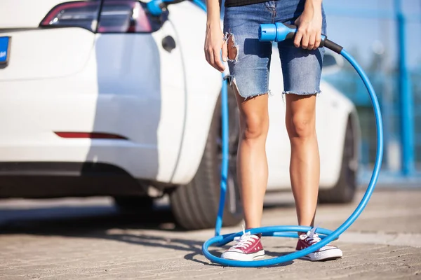 Fiatal Lány Egy Elektromos Autó Mellett Ügyetlen Töltőkábellel Lábai Körül — Stock Fotó