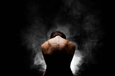 Yarı siluet modern balerin esmer arka planda dumanla poz veriyor.