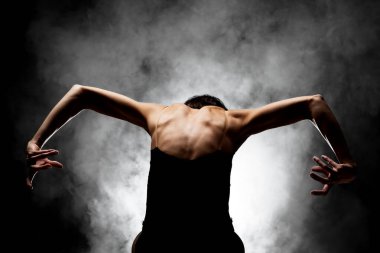 Yarı siluet modern balerin esmer arka planda dumanla poz veriyor.