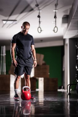 Kettlebell 'le poz veren kaslı bir sporcu. Adam içeride çalışıyor..