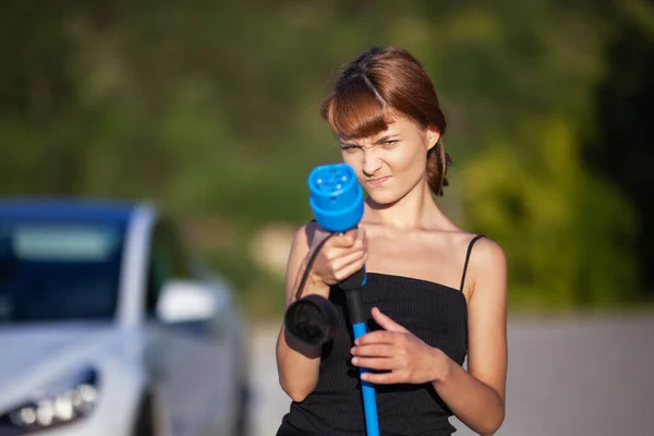 Όμορφη Νεαρή Κοπέλα Δίπλα Ένα Ηλεκτρικό Αυτοκίνητο Τοποθέτηση Και Συγκράτηση — Φωτογραφία Αρχείου
