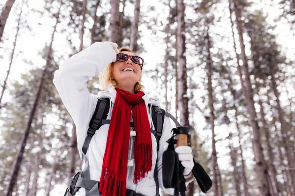 在冬天的一天 穿着红色和白色衣服的女孩在有雪的森林里徒步旅行 — 图库照片