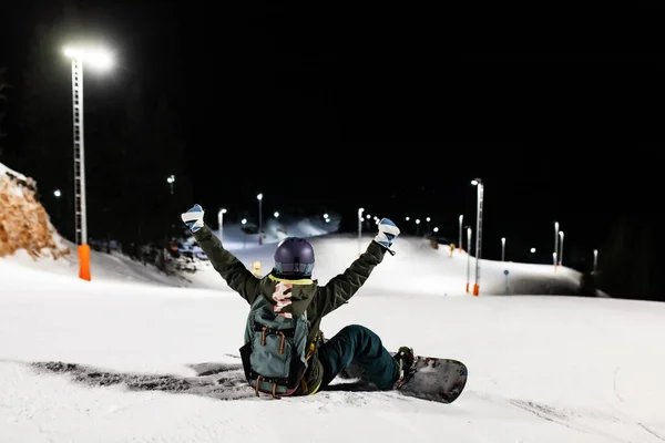 滑雪板上的女孩躺在斜坡上 冬季度假胜地的夜间滑雪 — 图库照片