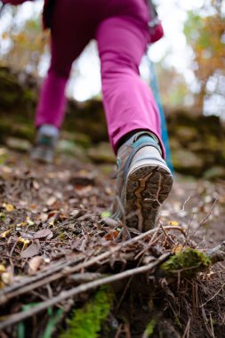 Dağda gezen kız. Sıradan spor ayakkabıları ve ormandaki bacaklar düşük açılı. Açık havada sağlıklı bir yaşam tarzı..