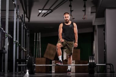 Ağırlık kaldırmaya hazırlanan bir sporcu. Spor salonunda poz veren kaslı bir adam..