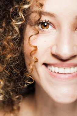 Uzun kıvırcık saçlı güzel esmer kız. Yakın çekim stüdyo portresi. Mutlu yüz ifadesi. 