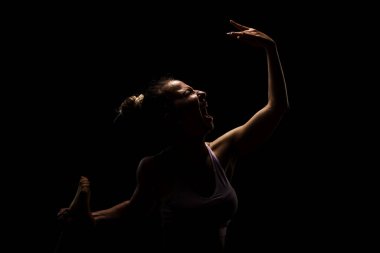 Stüdyoda yoga yapan formda bir kız. Yarı siluet yan aydınlatma fitness modeli