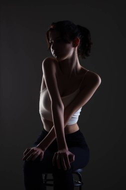 Stüdyoda karanlık arka planda güzel bir genç kızın yarım siluet portresini aydınlattım..