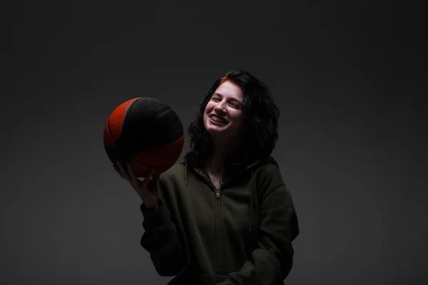 歯のブレースを持つ10代の女の子はバスケットボールを保持 暗い背景のスタジオの肖像画 — ストック写真