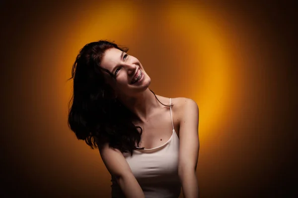 歯のブレースを持つ10代の少女 ネオンオレンジ色の背景のスタジオの肖像 — ストック写真