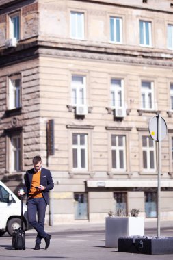 İş adamı tramvay bagajıyla seyahat ediyor, akıllı telefon kullanıyor ve kahve içiyor..