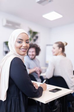 Sınıfta bir öğretim üyesini dinleyen çok ırklı öğrenciler. Zeki Afro-Amerikan kadın gülümsüyor ve kameraya poz veriyor..