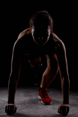 Yandan aydınlatılmış siluet formundaki kız yarışa koyu arkaplanda başlıyor..