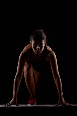 Yandan aydınlatılmış siluet formundaki kız yarışa koyu arkaplanda başlıyor..