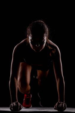 Yandan aydınlatılmış siluet formundaki kız yarışa koyu arkaplanda başlıyor..