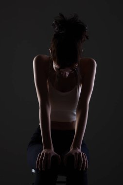 Stüdyoda karanlık arka planda güzel bir genç kızın yarım siluet portresini aydınlattım..