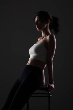 Stüdyoda karanlık arka planda güzel bir genç kızın yarım siluet portresini aydınlattım..