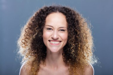 Uzun kıvırcık saçlı güzel esmer kız. Stüdyo portresi. Mutlu gülen yüz ifadesi.