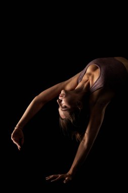 Yoga pozu veren zinde bir kadın. Stüdyoda siyahlara karşı egzersiz yapan yarım siluet kız..