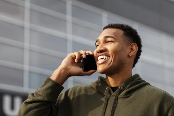 young african american man in casual outfit standing and talking on phone