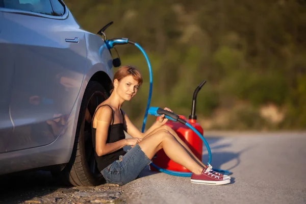 Üzgün Kız Yerde Elektrikli Arabanın Yanında Oturuyor Şarj Kablosu Kırmızı — Stok fotoğraf