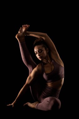 Yoga pozu veren zinde bir kadın. Stüdyoda siyahlara karşı egzersiz yapan yarım siluet kız..