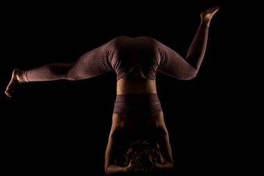 Yoga pozu veren zinde bir kadın. Stüdyoda siyahlara karşı egzersiz yapan yarım siluet kız..