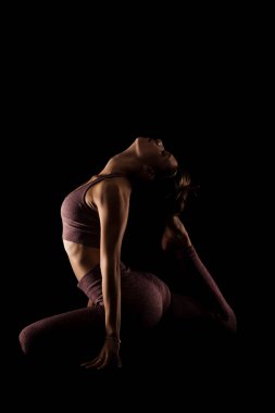 Yoga pozu veren zinde bir kadın. Stüdyoda siyahlara karşı egzersiz yapan yarım siluet kız..