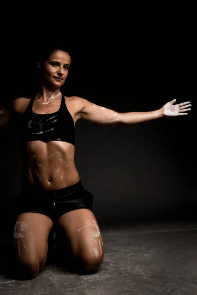 地面にスポーツウェアを着たセクシーなフィットの女の子 彼女の体に手のマグネシウム粉末プリント — ストック写真
